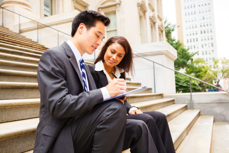 Man and woman dressed professionally working on the outside steps of a building